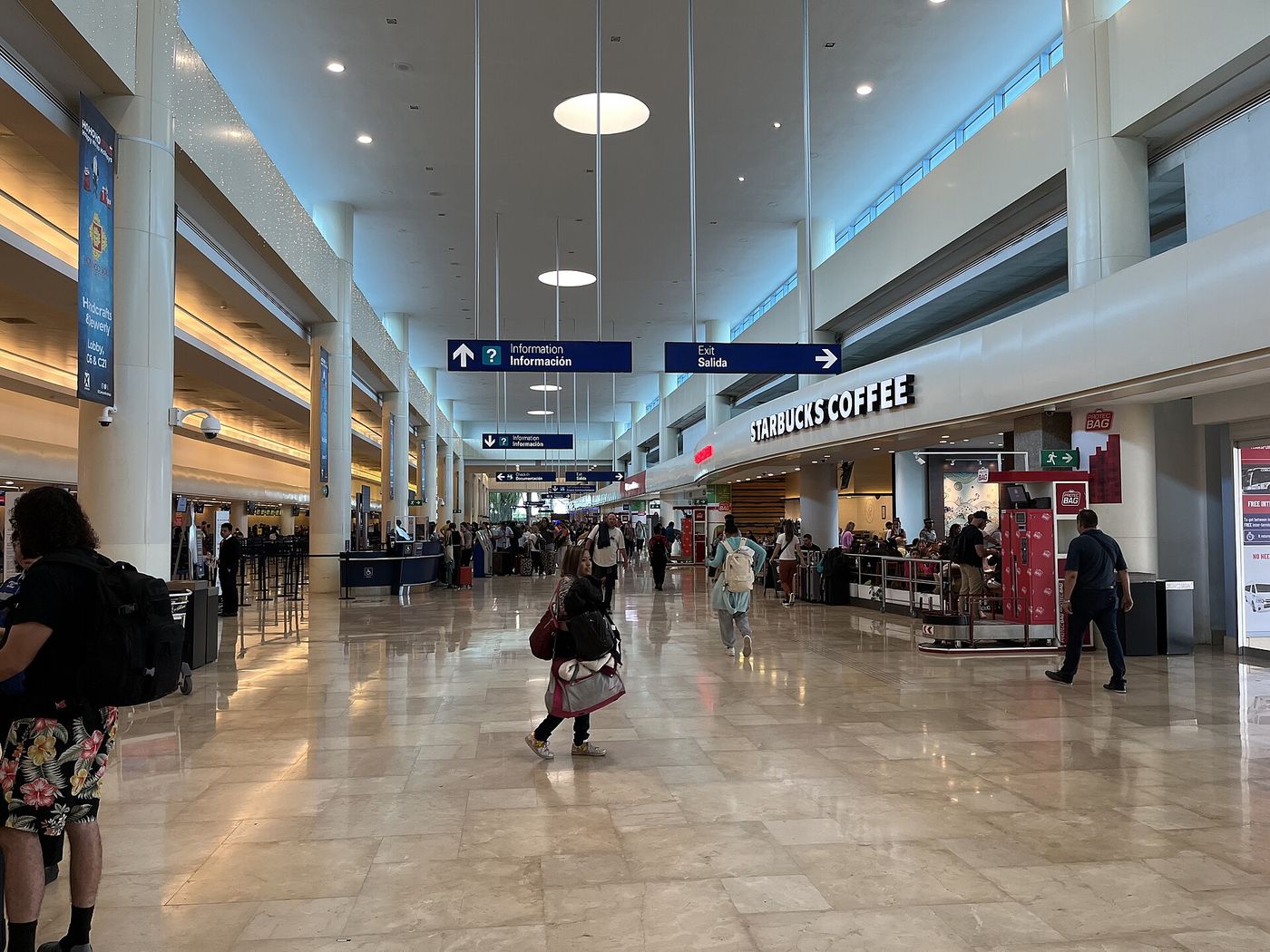 Viajeros con maletas saliendo por las puertas de llegadas del Aeropuerto Internacional de Cancún