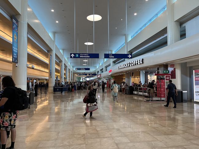 Viajeros con maletas saliendo por las puertas de llegadas del Aeropuerto Internacional de Cancún